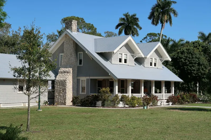 A residential home surrounded by palm trees and a green lawn