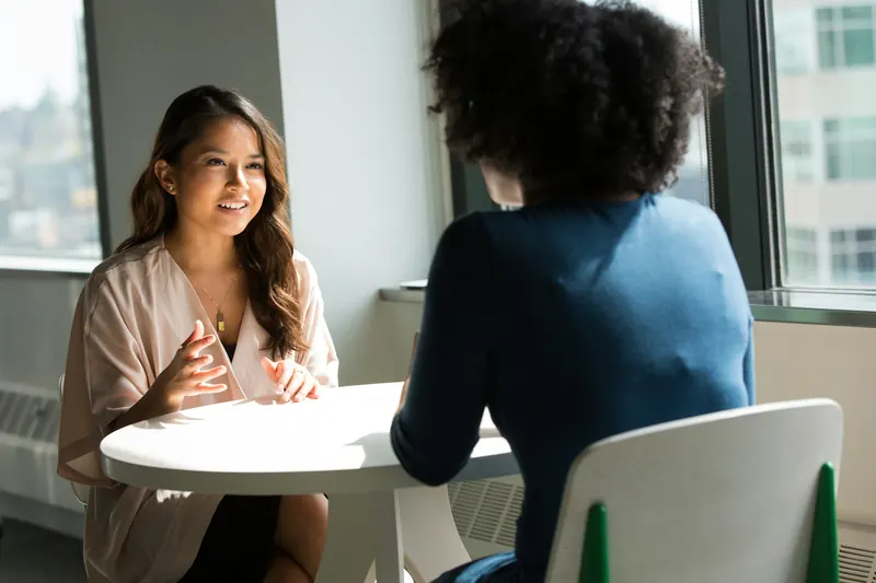 A counselor and a client talking at a table in a bright room