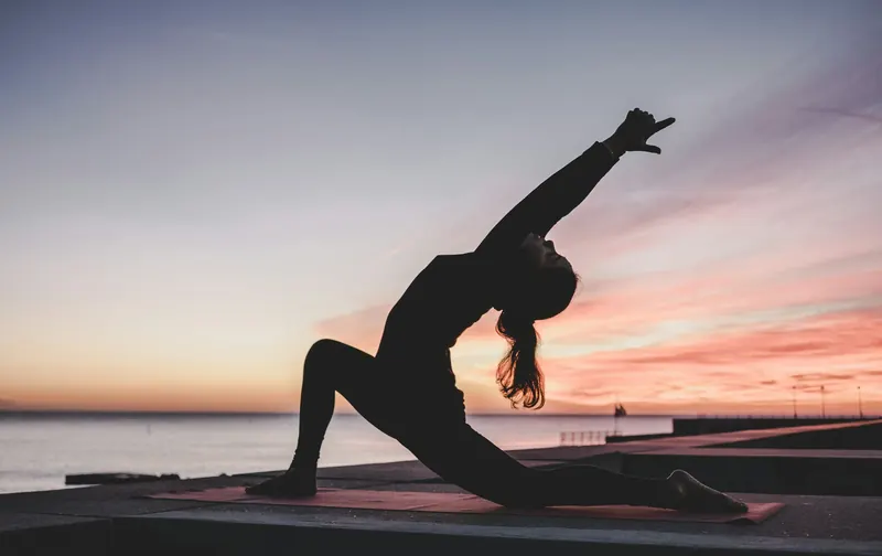 A woman practicing yoga at sunrise on the beach