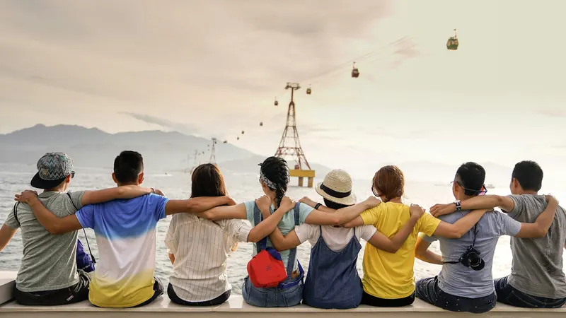 A group of friends sitting together outdoors with their arms around each other